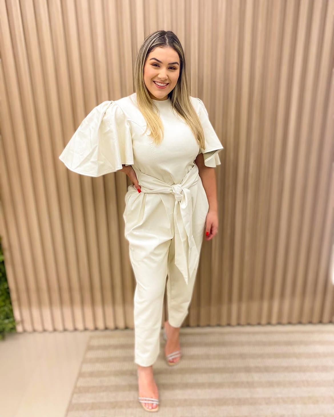Dra. Bruna Paloma sorrindo, com look off-white, na clínica Aura